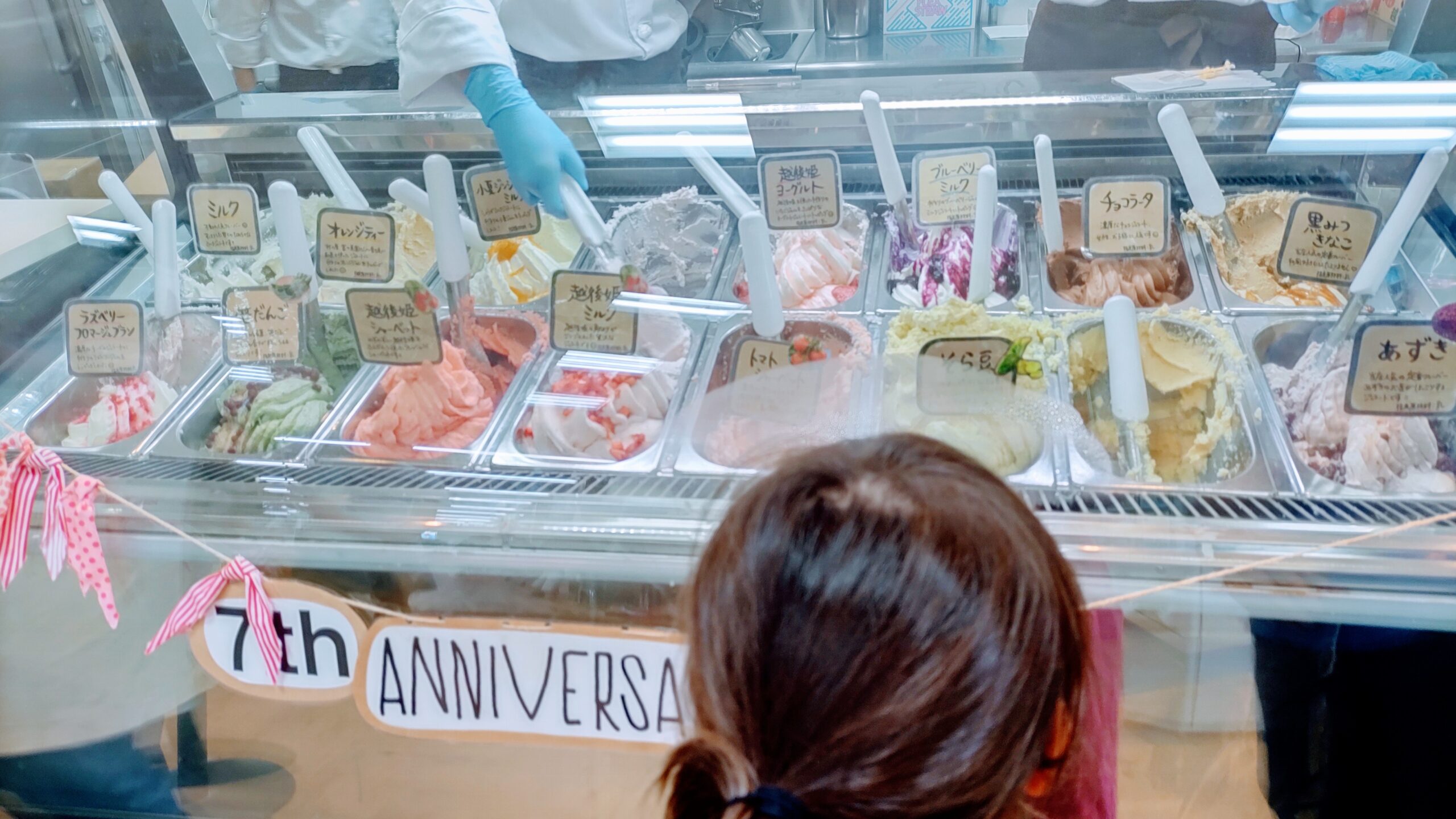 ご当地アイスがショーケースにずらりと並んでいる。それを覗いているこども。